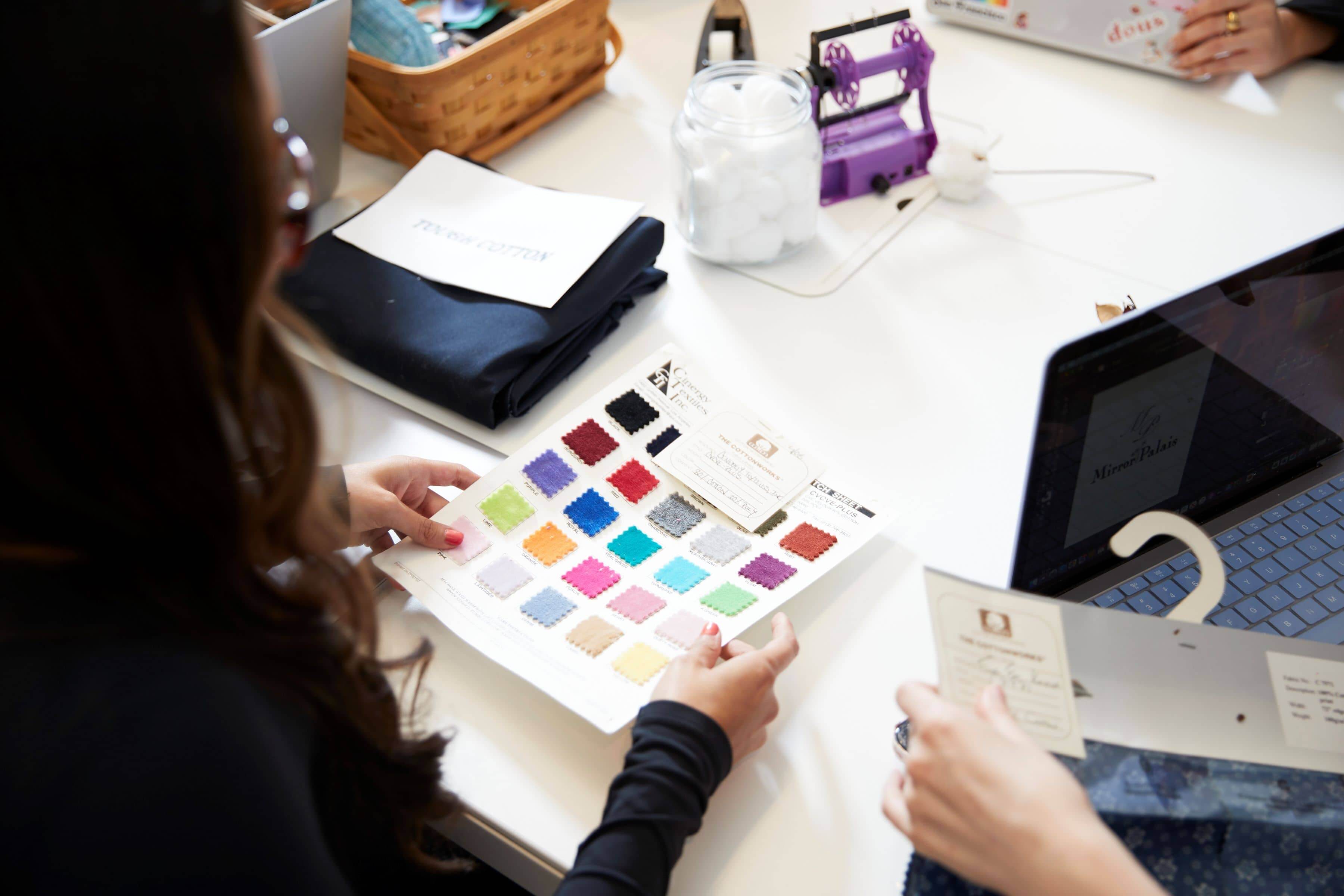 An LIM student holds a piece of paper 25 different-colored cloth samples