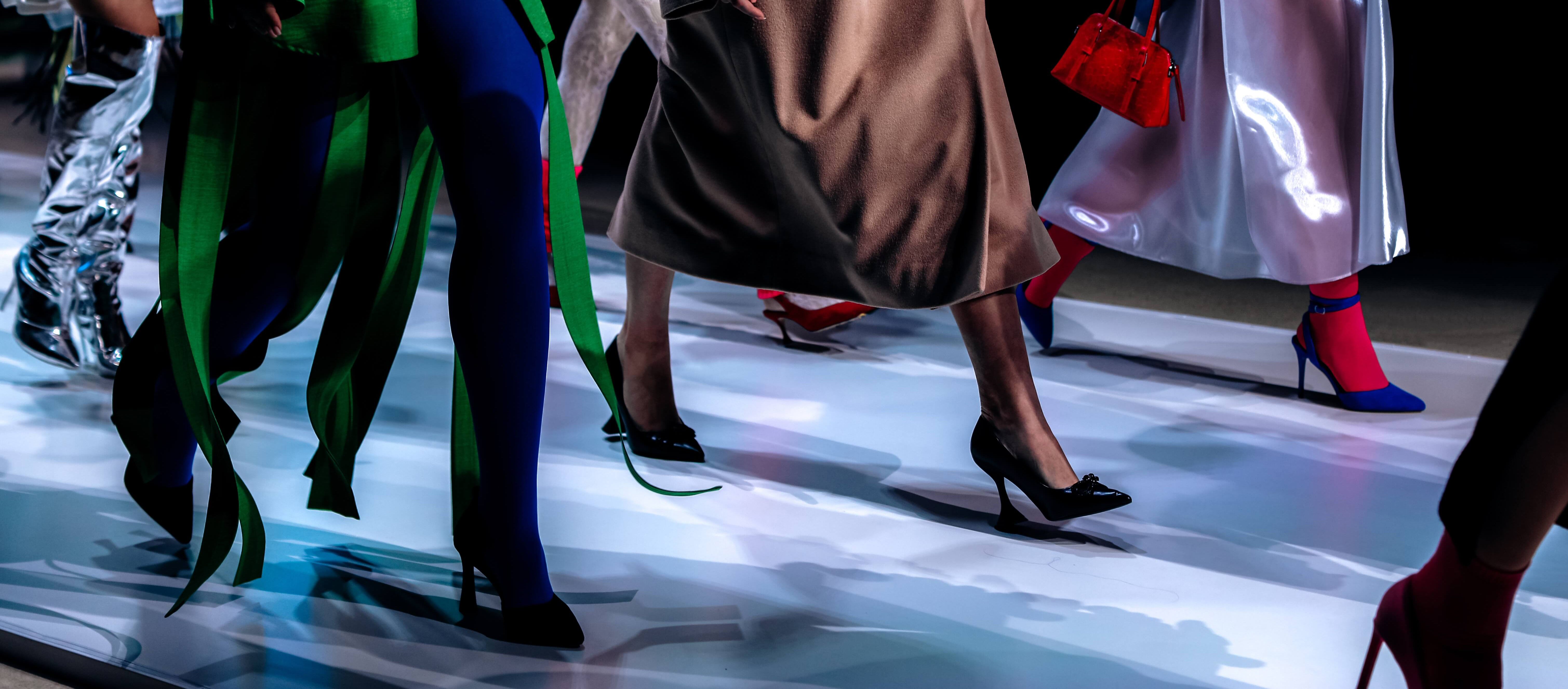 Models from neck down on runway, multicolored clothes and accessories