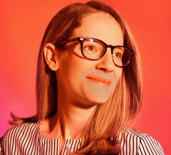 woman with glasses in front of orange wall